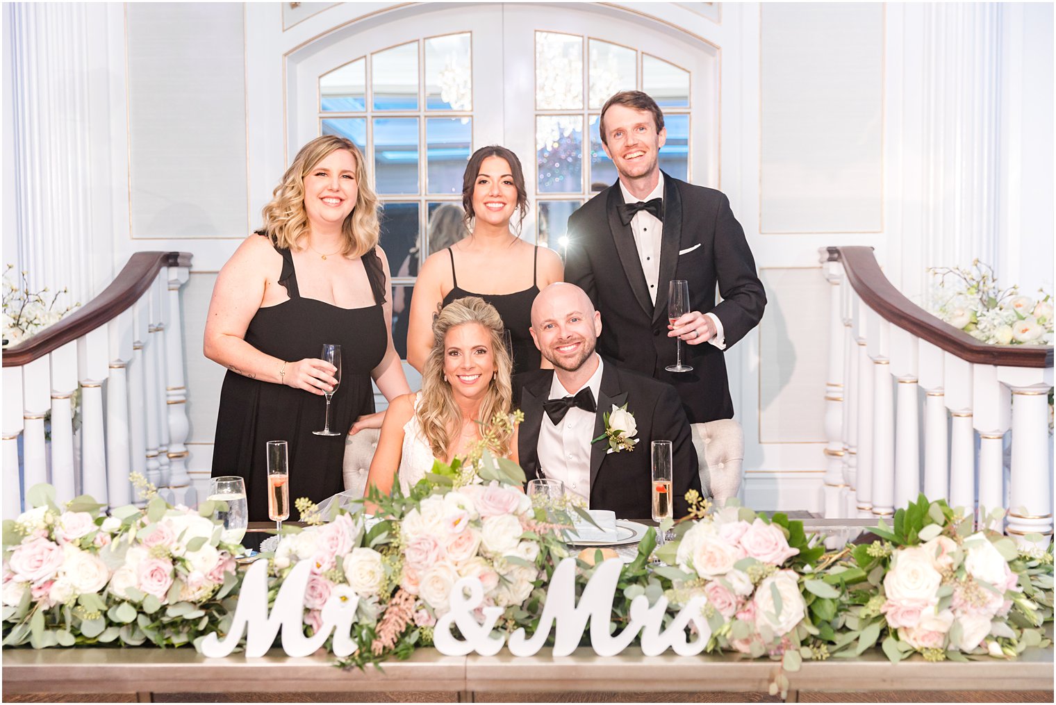  bride and groom sit with maid and matron of honor and best man with them