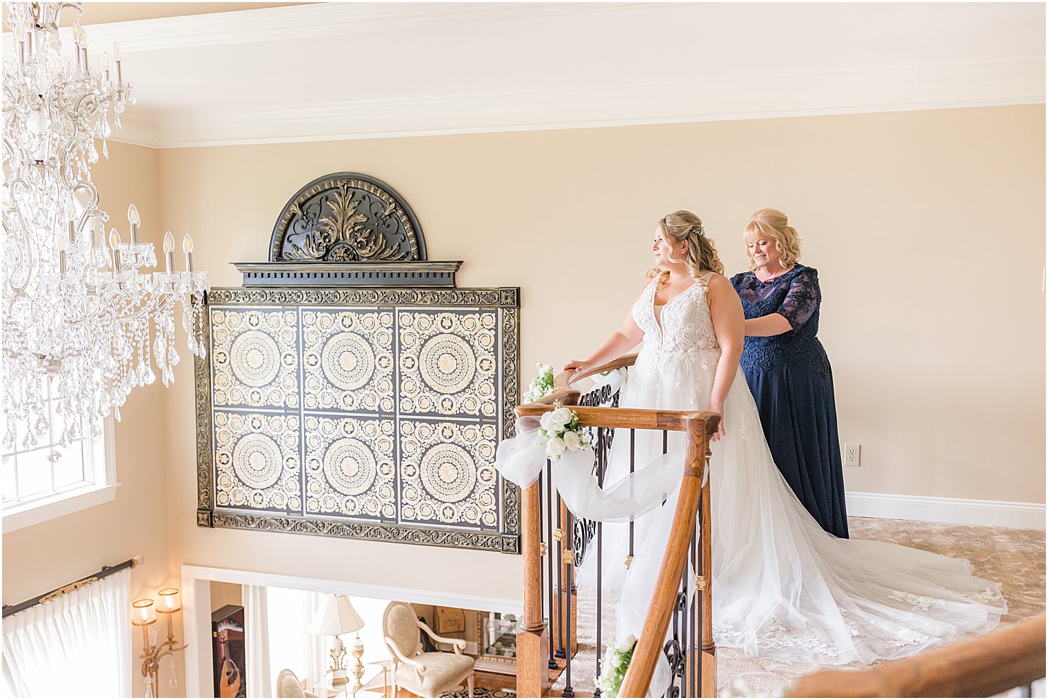 mother in navy dress helps bride into wedding gown