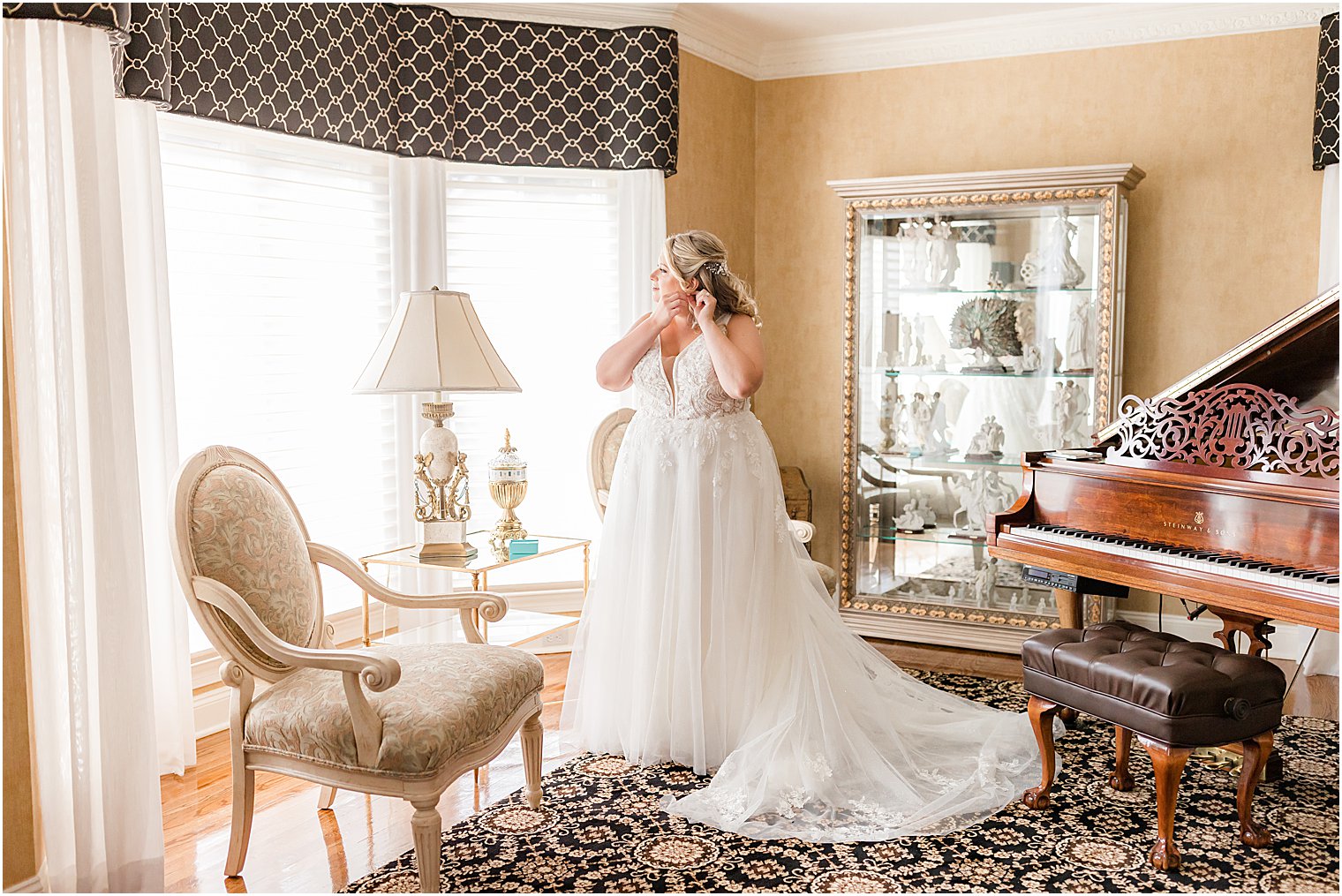 bride puts in earrings standing by window and piano at home