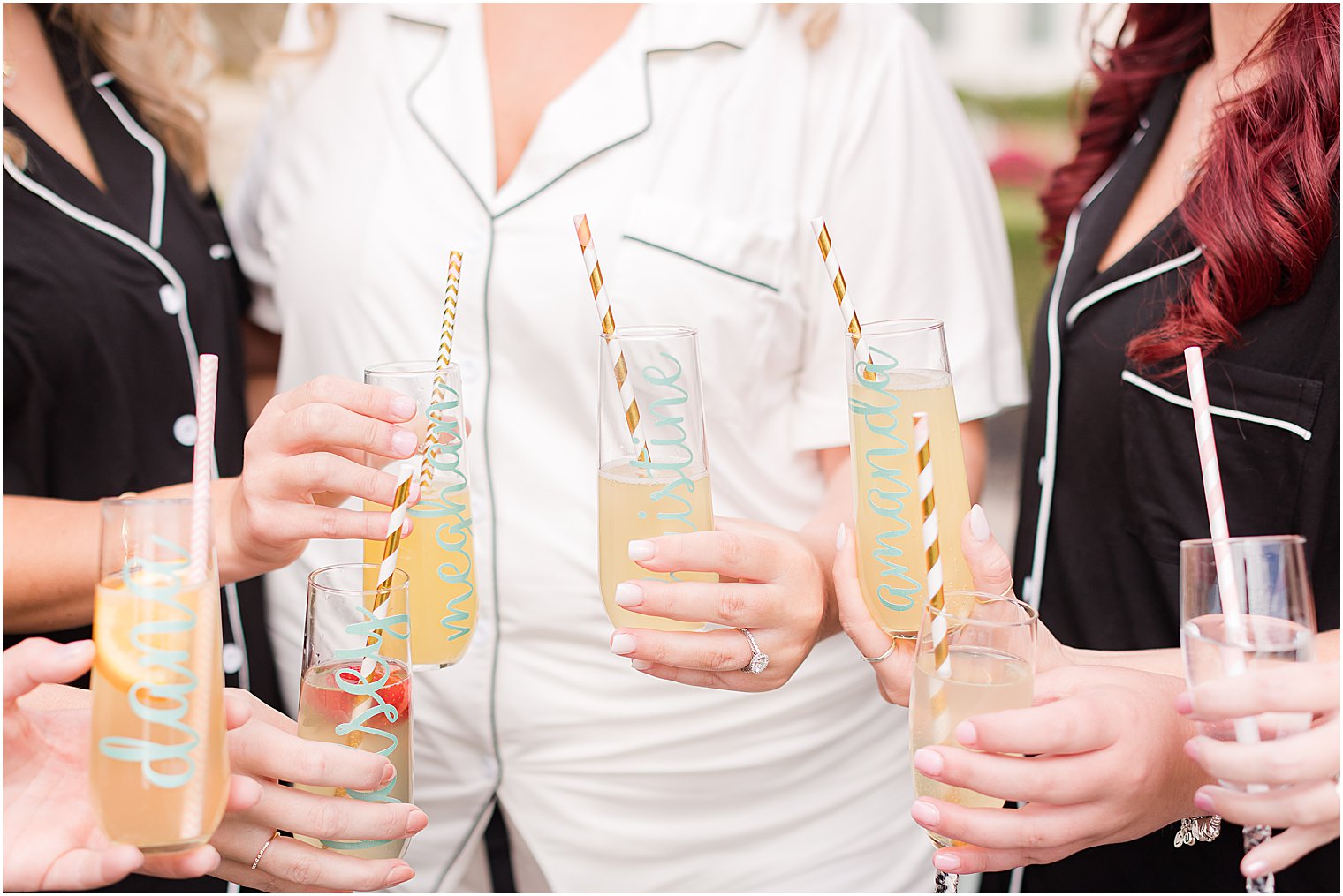 bridesmaids hold champagne glasses with striped straws 