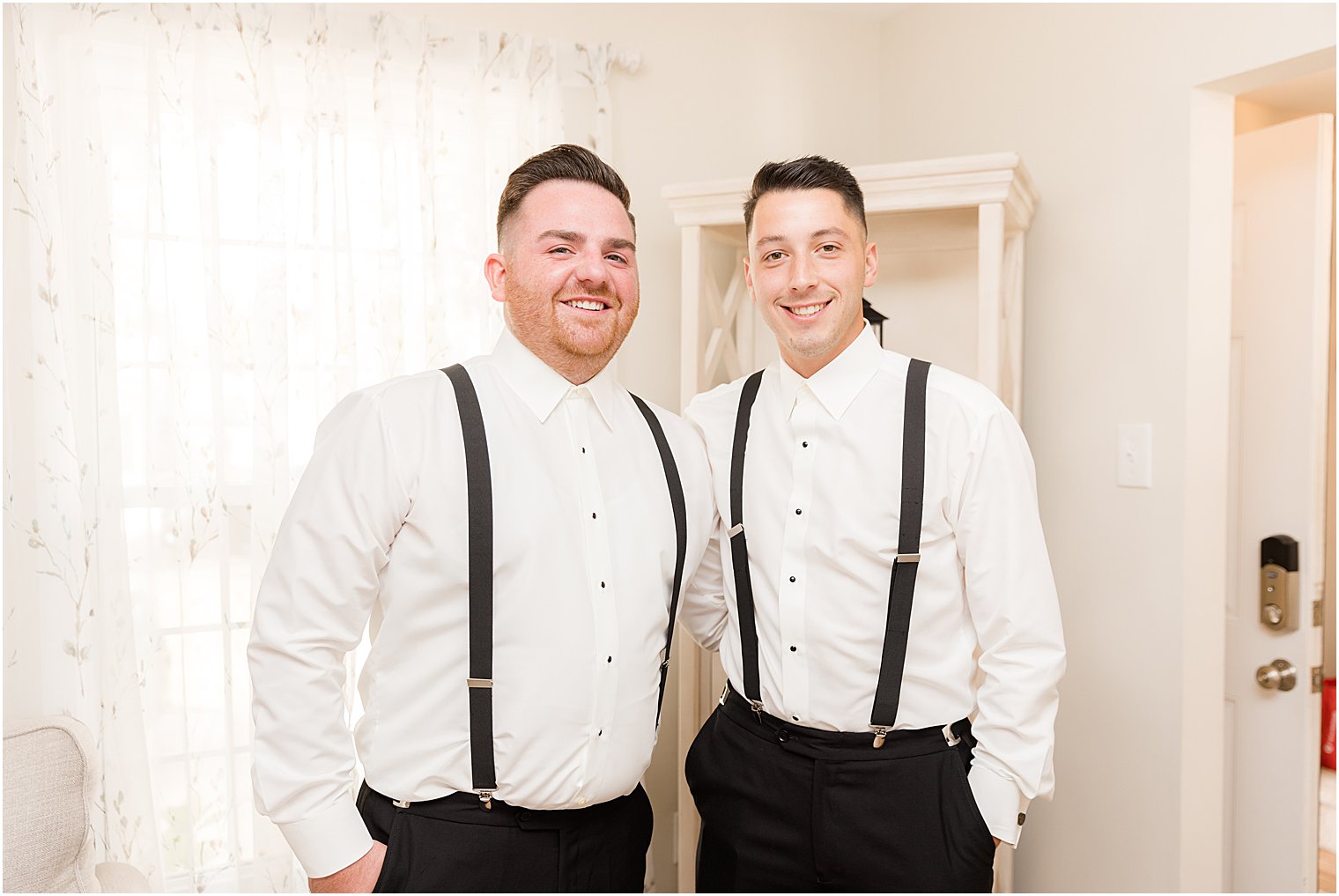 groom stands with best man in suspenders