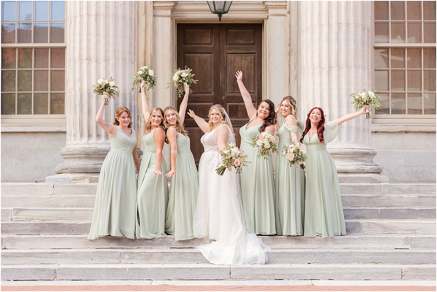 bride and bridesmaids cheer standing on steps of the First National Bank in Philly, PA