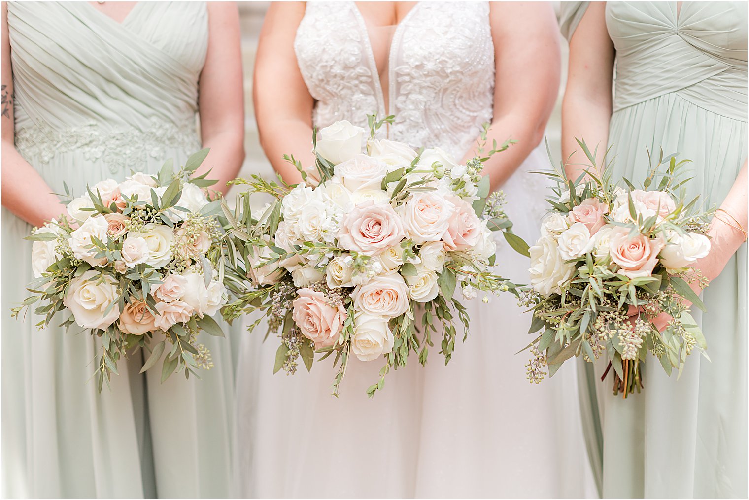 bride and bridesmaids hold boquets of pink and white flowers 