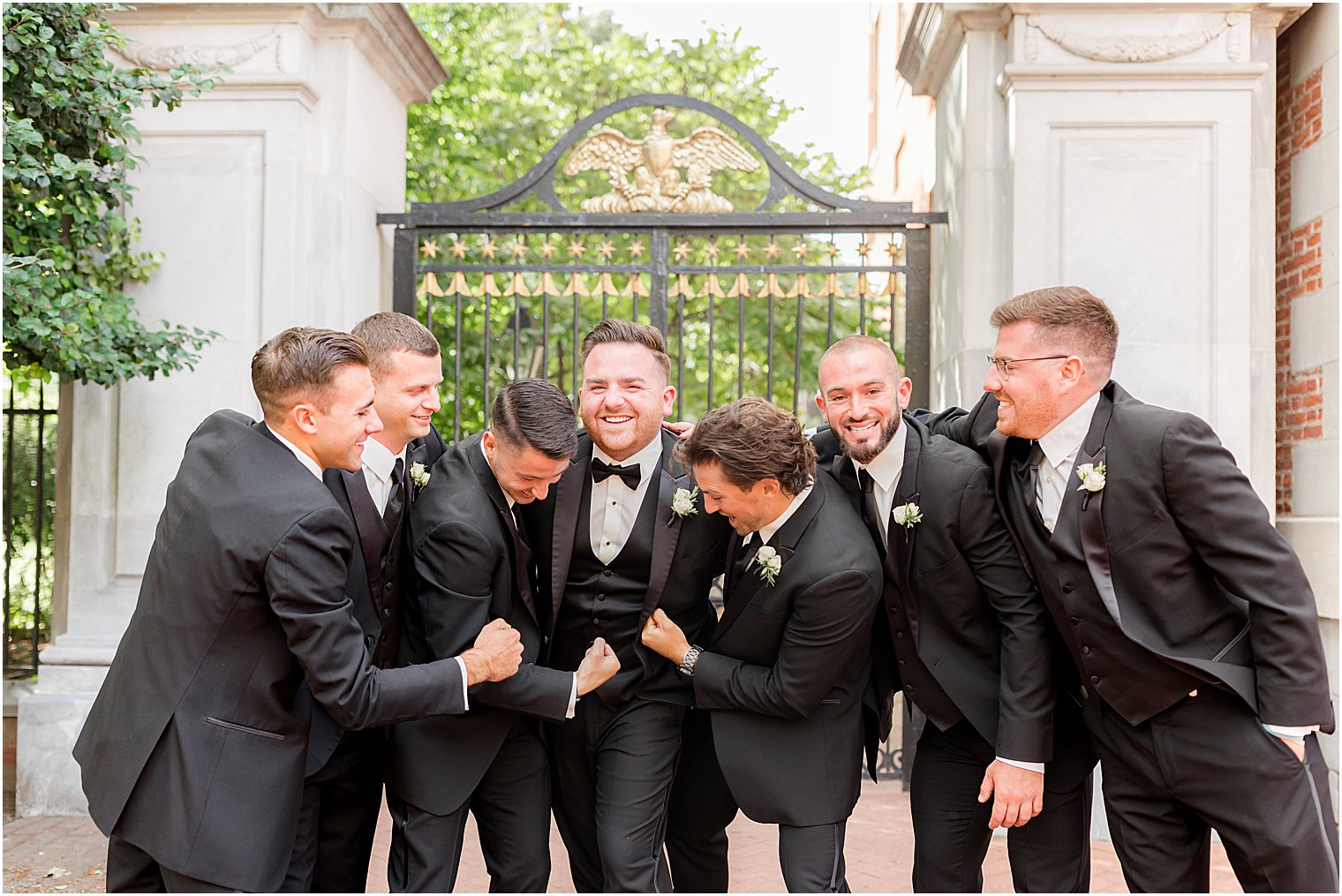 groomsmen tickle groom outside gate of Benjamin Rush Gardens