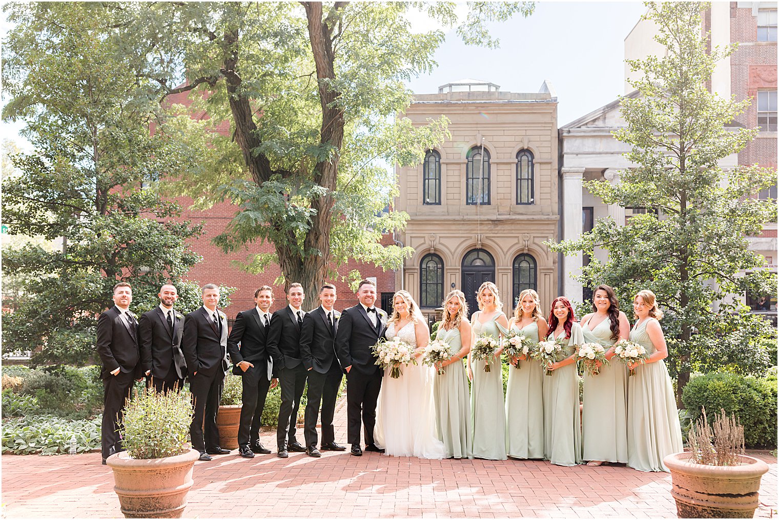 bride and groom stand with wedding party outside Benjamin Rush Gardens