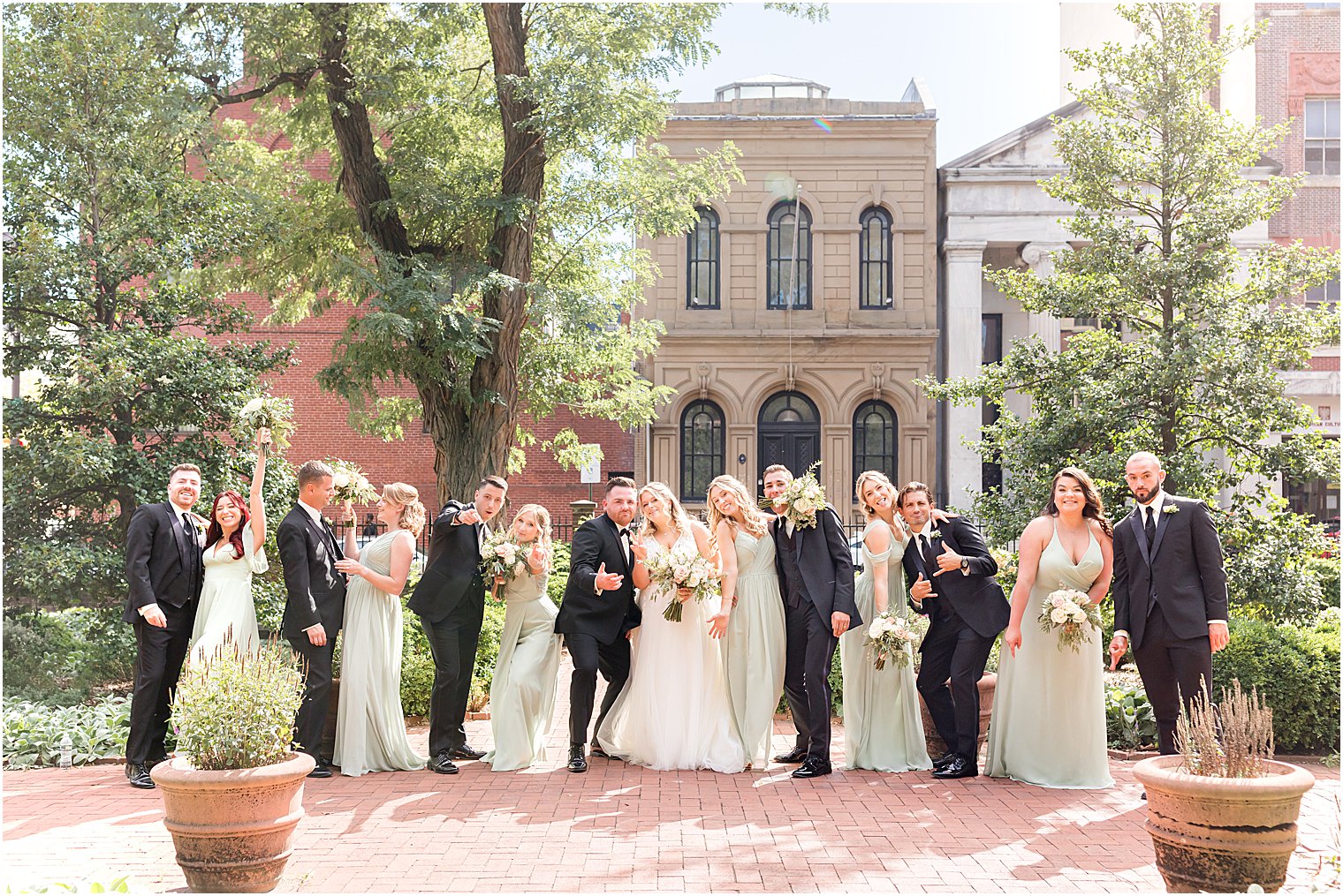 newlyweds kiss with wedding party around them in Philly PA