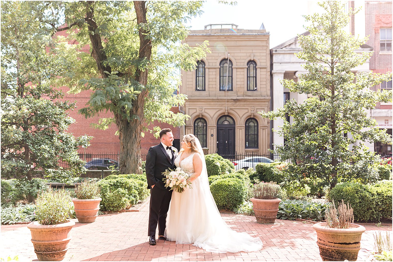 bride and groom hug on brick patio at Benjamin Rush Gardens