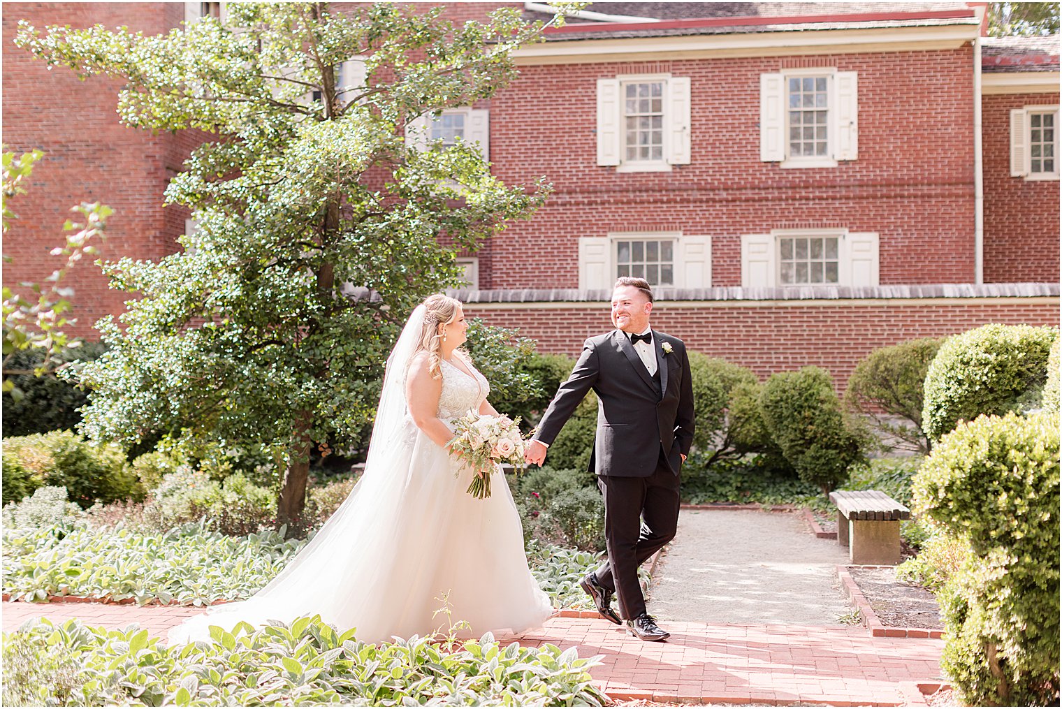 groom leads bride through Benjamin Rush Gardens