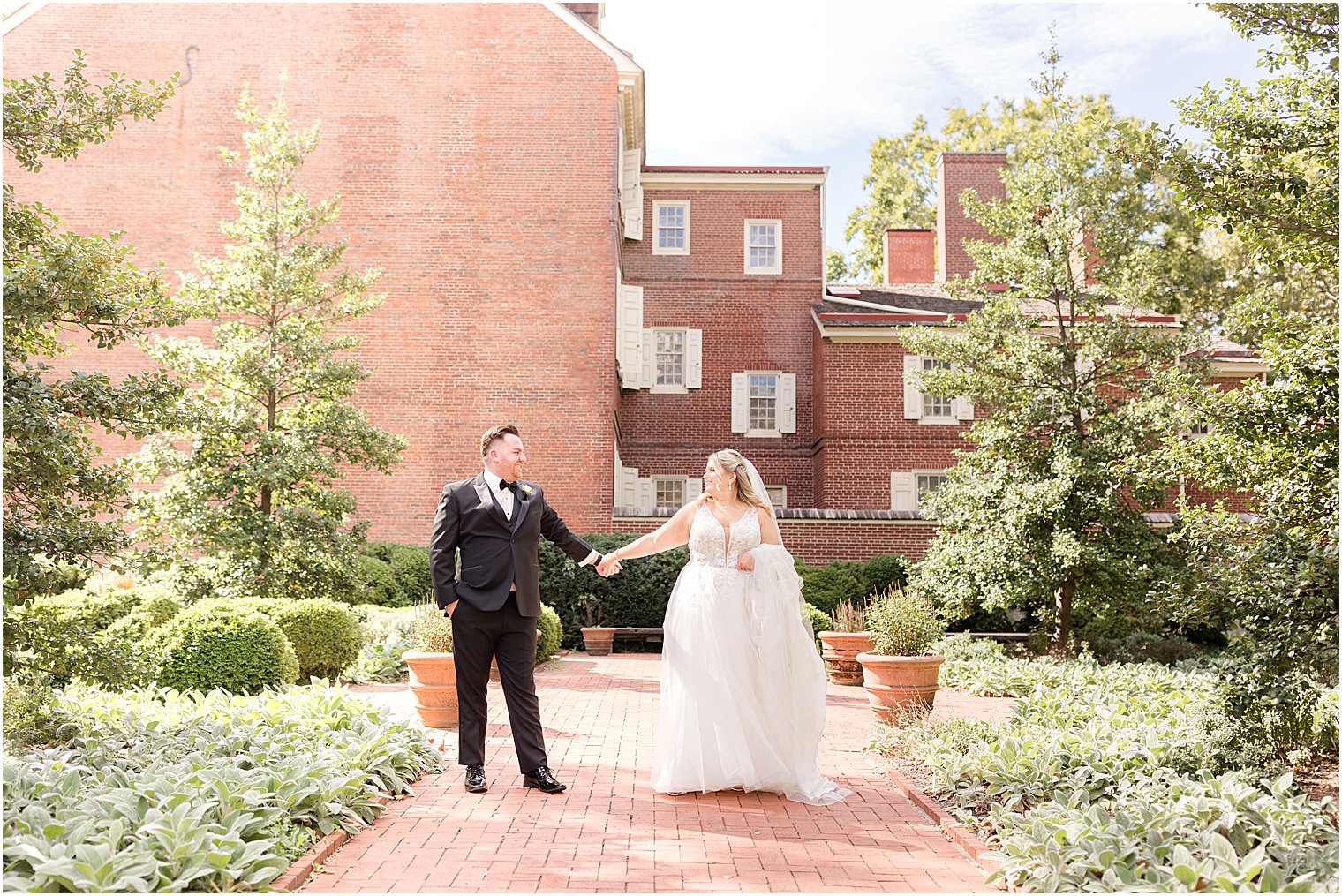 bride and groom hold hands walking through Benjamin Rush Gardens