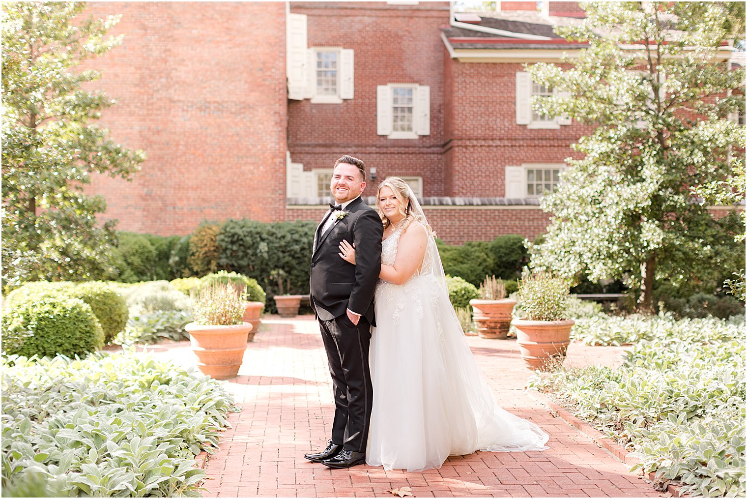 bride hugs groom standing inside Philly gardens