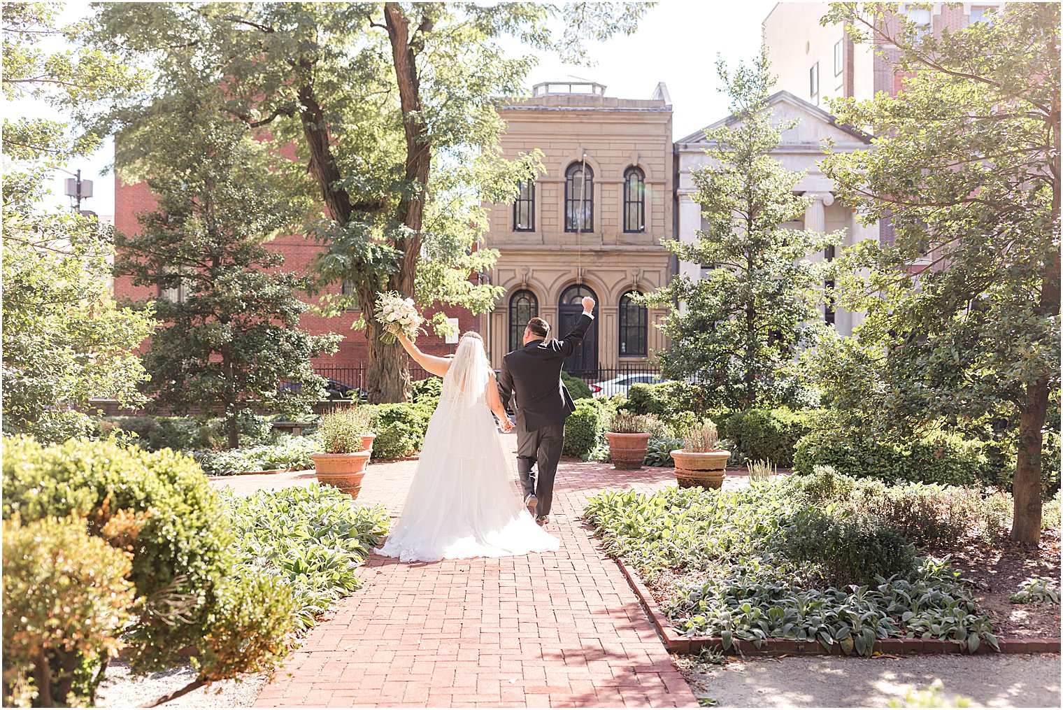 couple walks away through Benjamin Rush Gardens cheering 