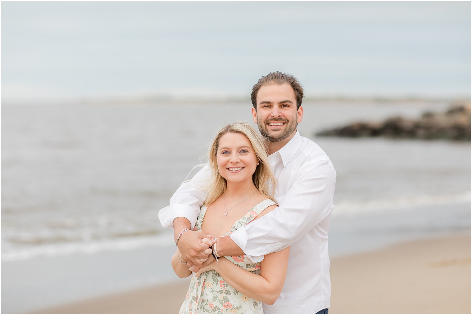 groom hugs bride from behind during Union Beach engagement session 