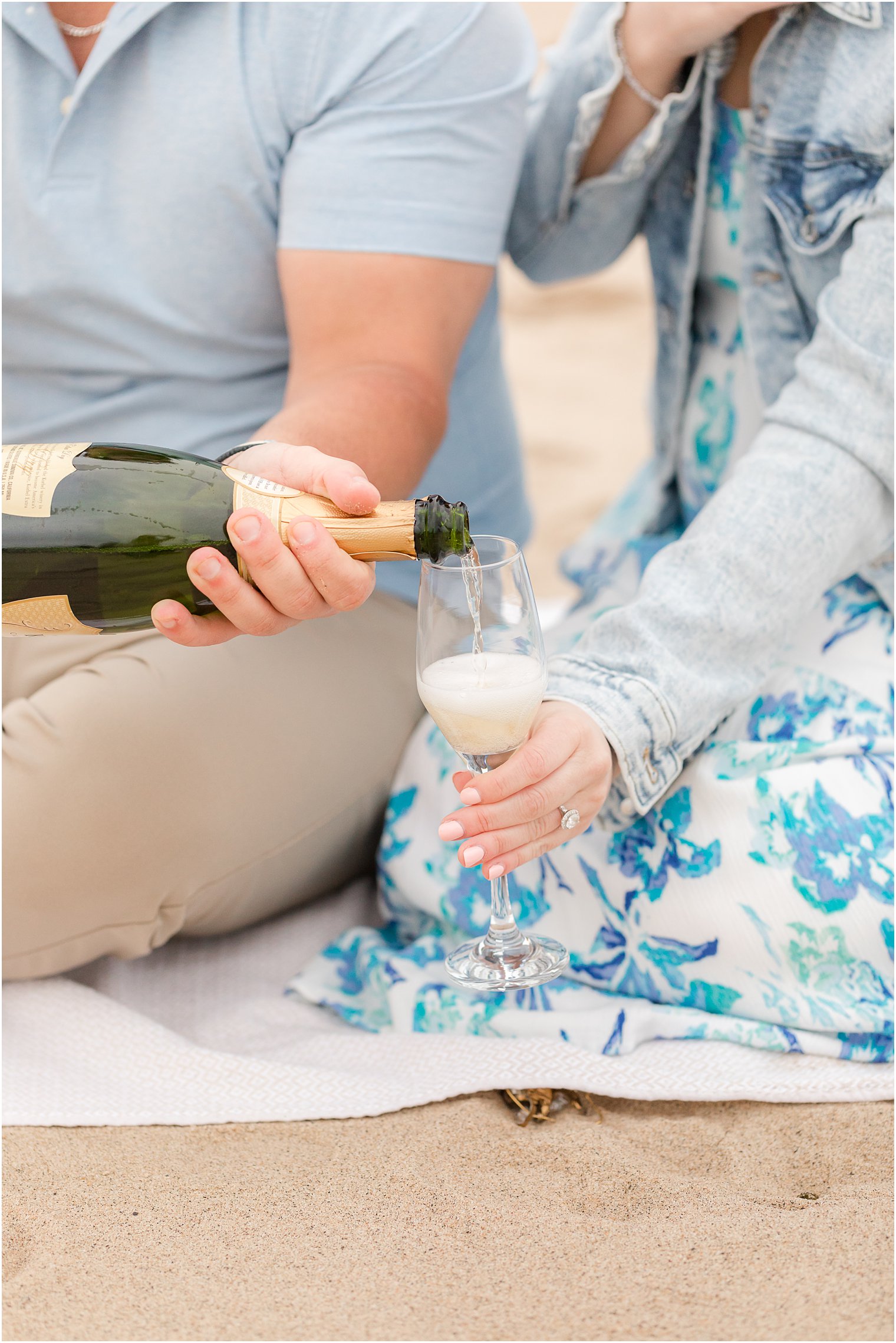 groom pours champagne for bride during Union Beach engagement session 