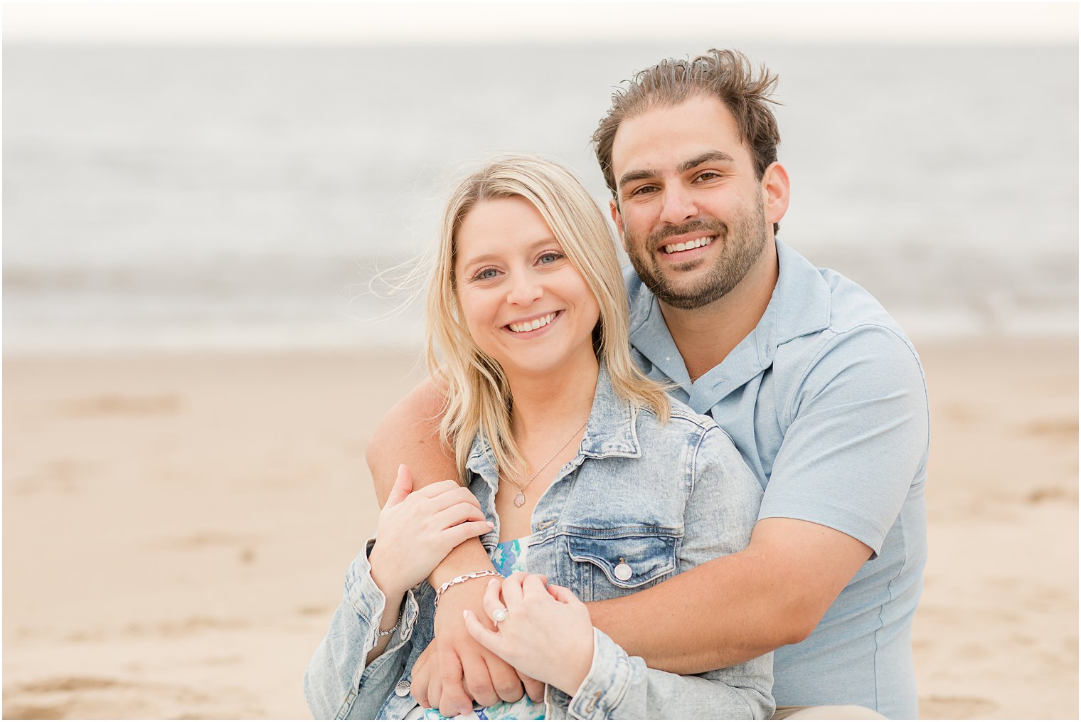 bride and groom hug on beach during Union Beach engagement session 