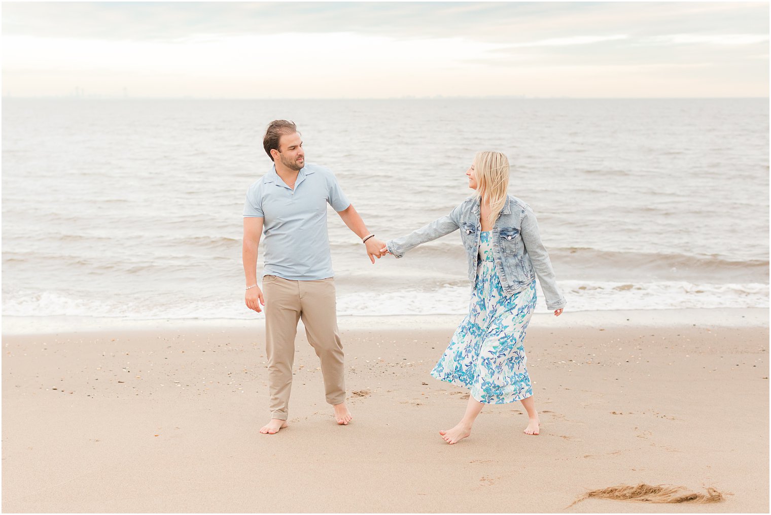 bride and groom hold hands walking on sand during Union Beach engagement session