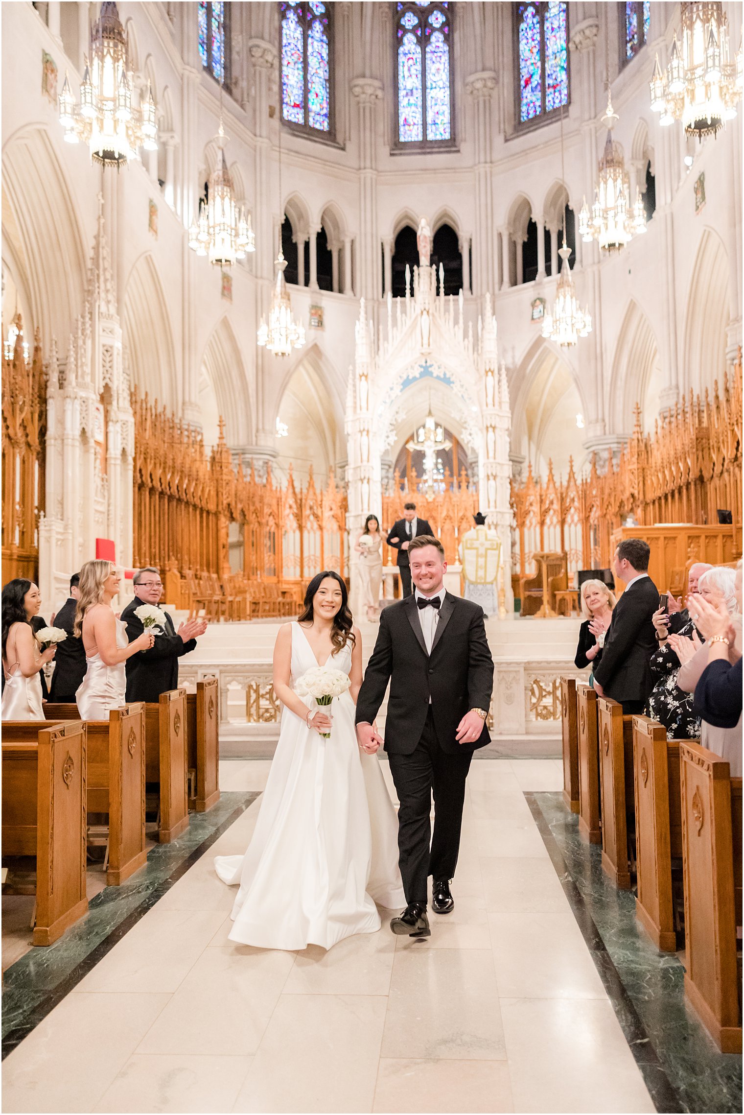 bride and groom hold hands walking up aisle in The Cathedral Basilica of the Sacred Heart