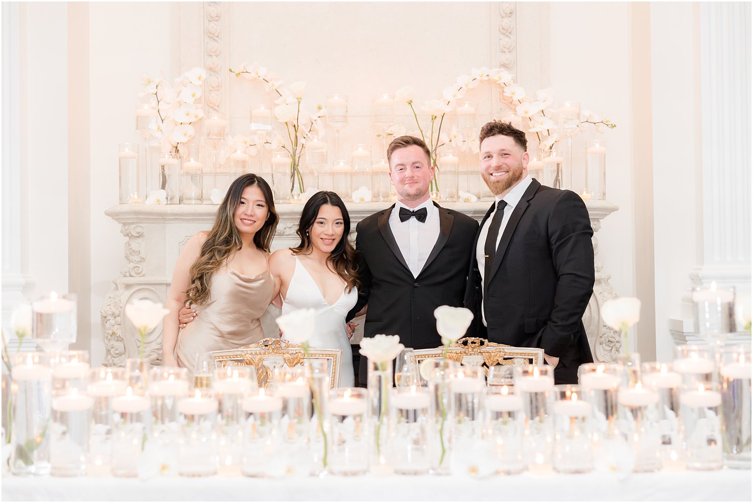 bride and groom pose with best man and MOH at head table 