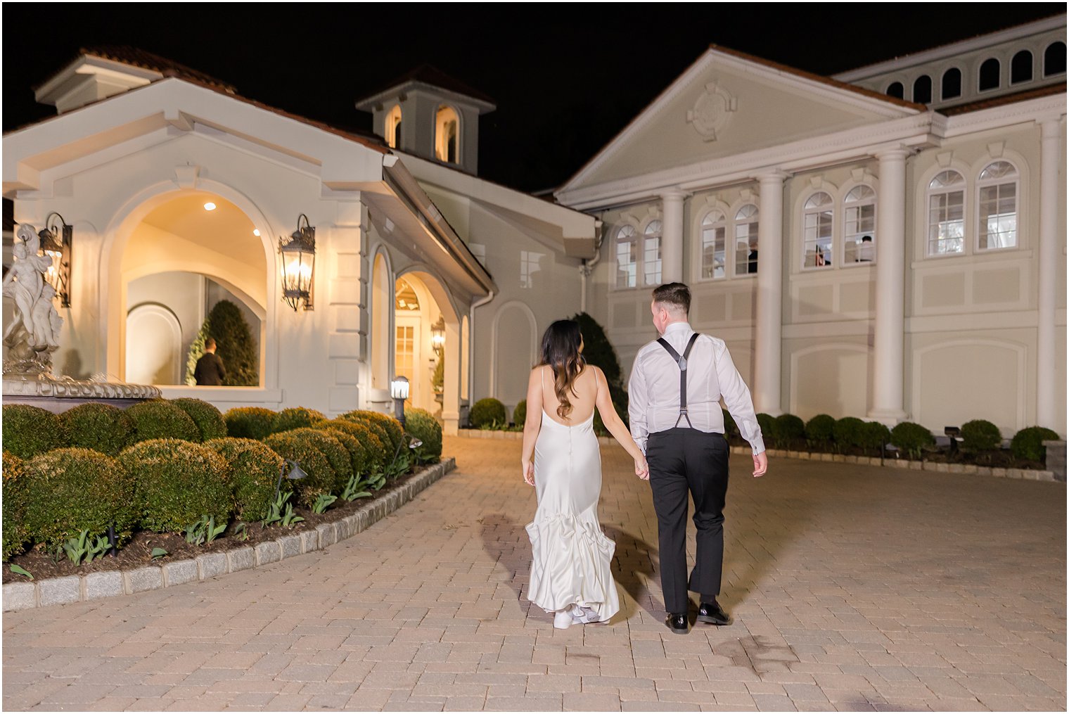 bride and groom hold hands walking into Nanina's in the Park at night 