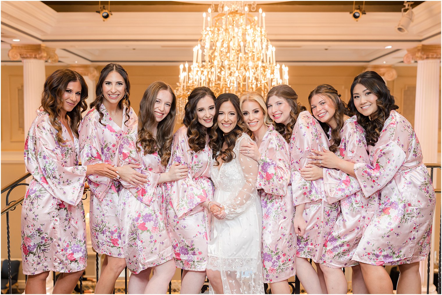 bride hugs bridesmaids in matching pink robes inside The Palace at Somerset Park