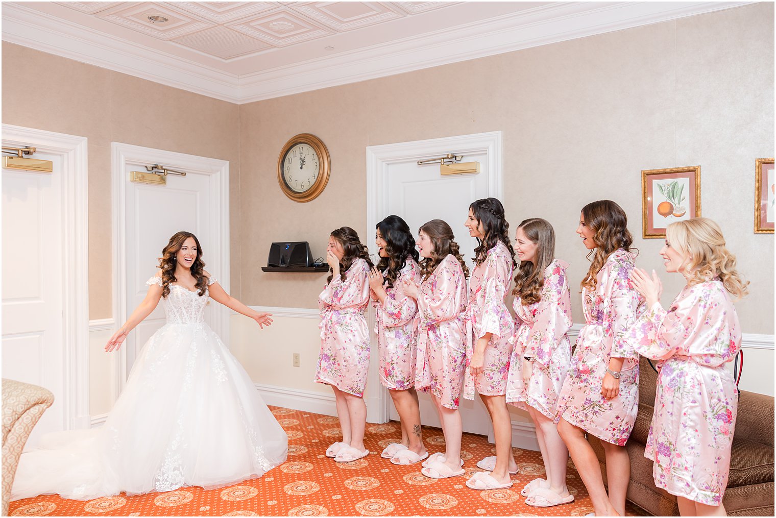 bride in wedding gown with big skirt shows off to bridesmaids 
