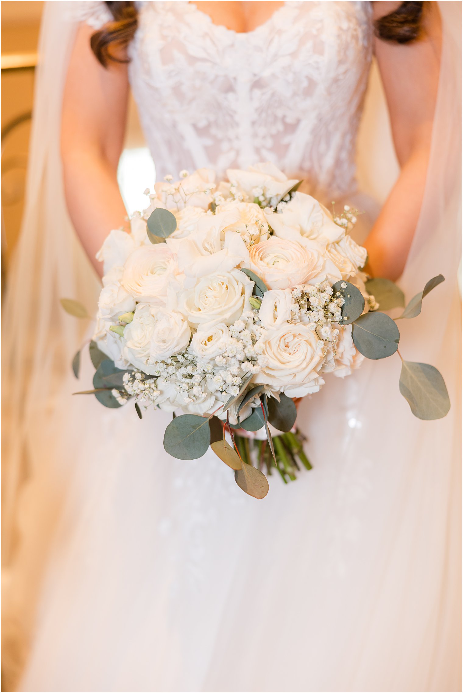 bride holds bouquet of ivory roses in front of corset bodice 