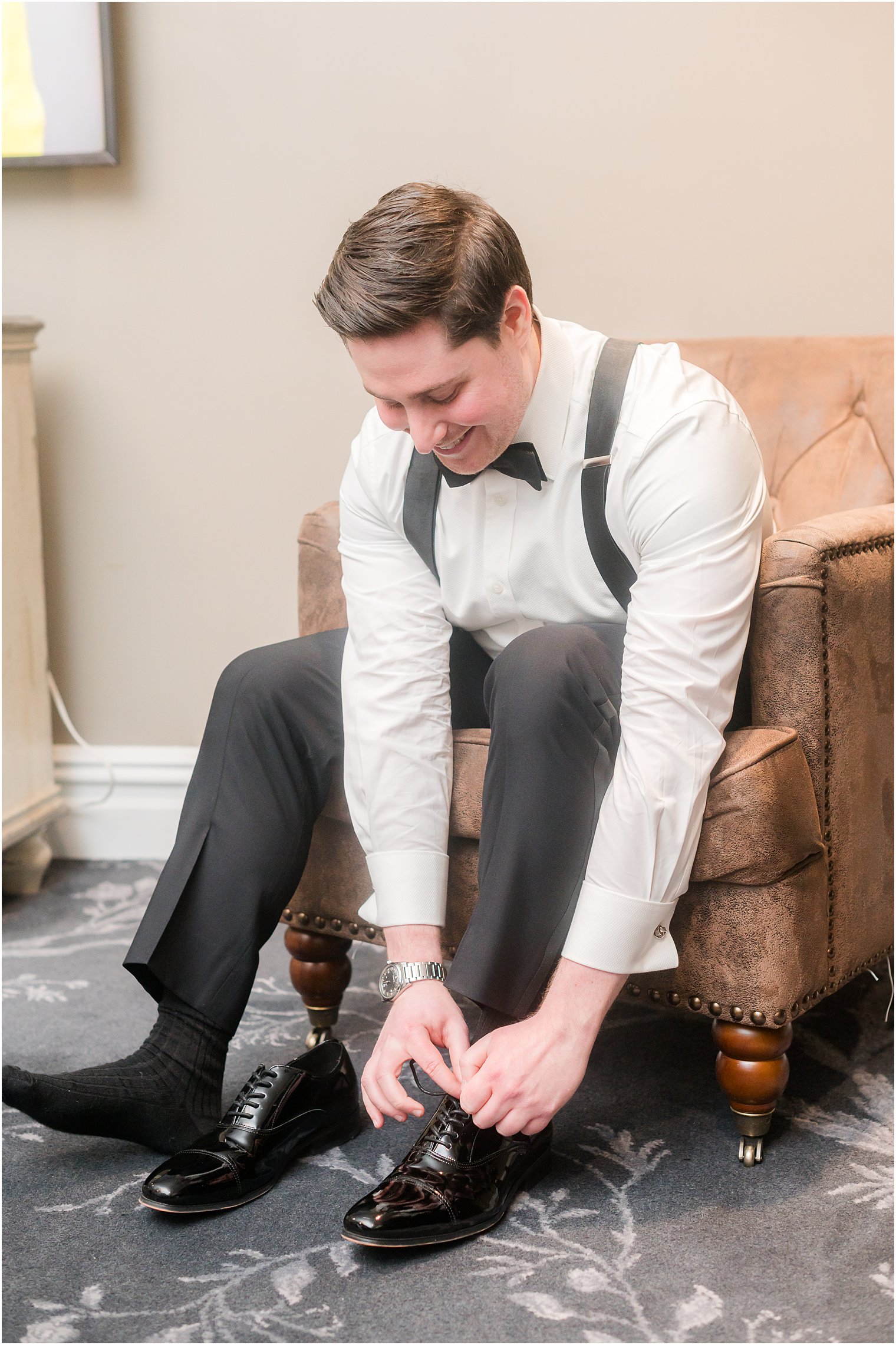 groom leans down to tie shoes at the Palace at Somerset Park