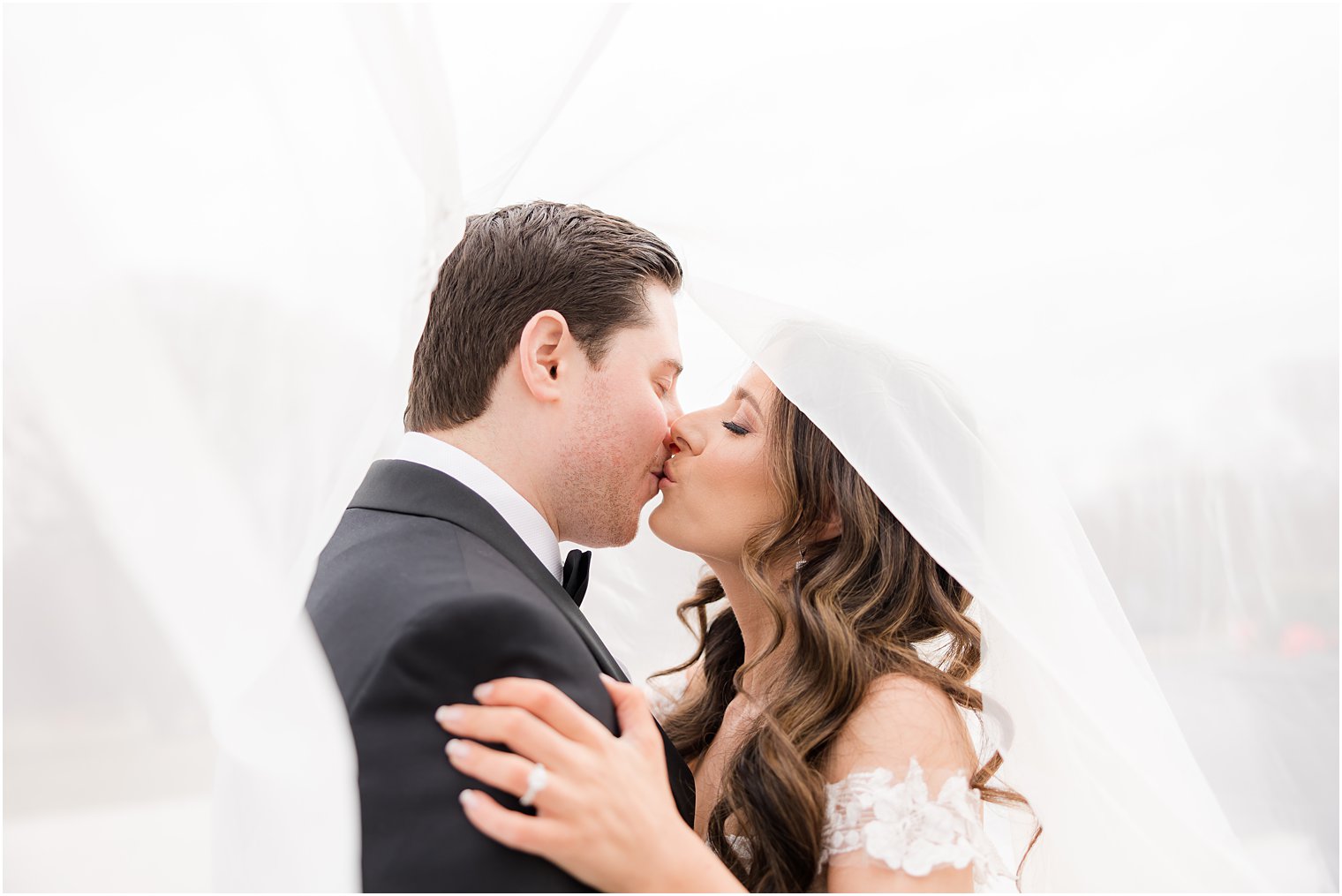 bride and groom kiss under bride's veil