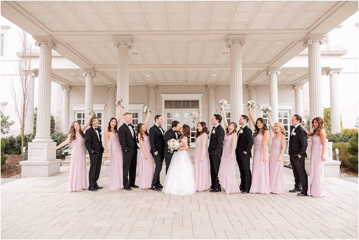 newlyweds kiss while wedding party cheers for them 