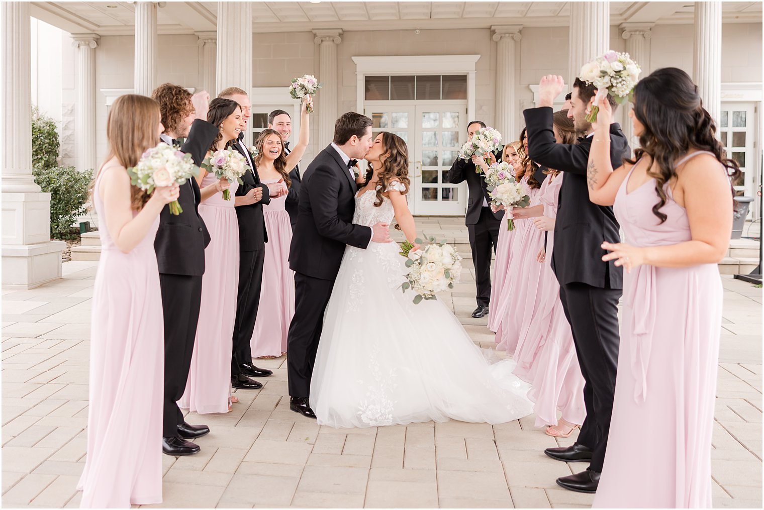 bride and groom kiss between rows of bridesmaids and groomsmen outside the Palace at Somerset Park