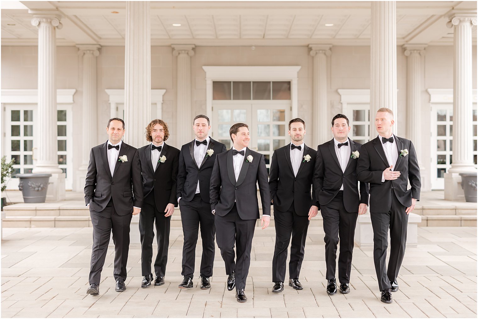 groom walks with groomsmen in front of the Palace at Somerset Park