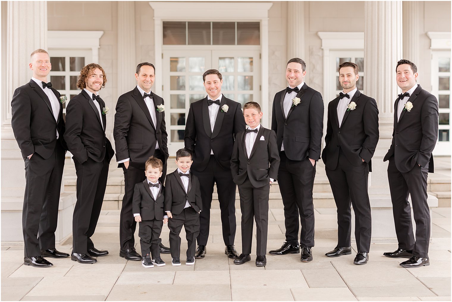 groom poses with groomsman in black suits outside the Palace at Somerset Park