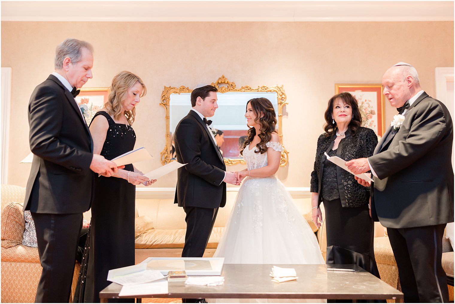 bride and groom hold hands while parents read during Ketbuah signing