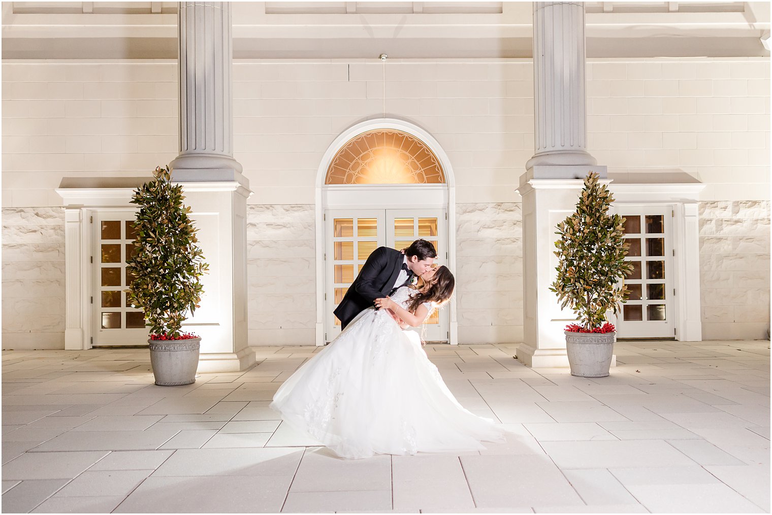 groom dips bride outside white building at the Palace at Somerset Park