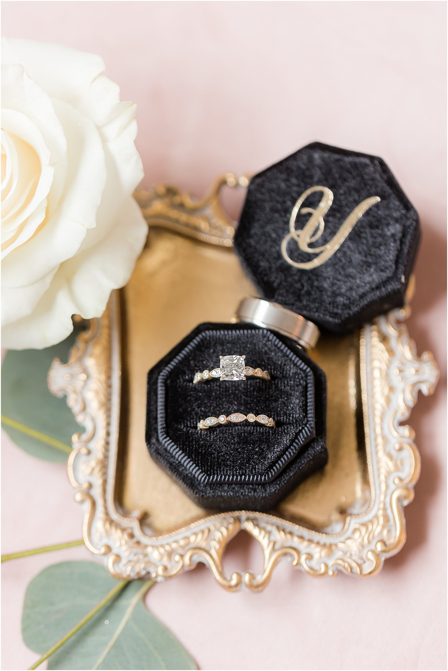 wedding rings rest in black ring box on gold tray