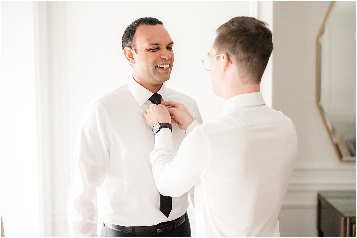 groomsman adjusts tie for groom before NJ wedding