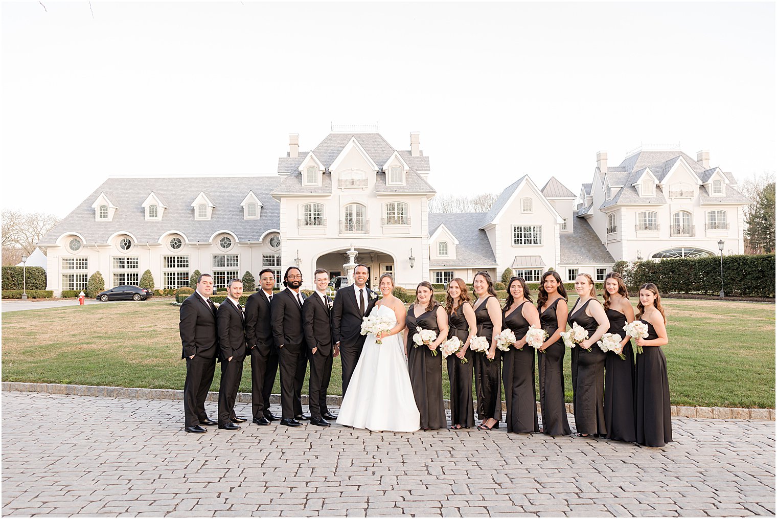 bride and groom stand with bridal party in black attire at Park Chateau Estate