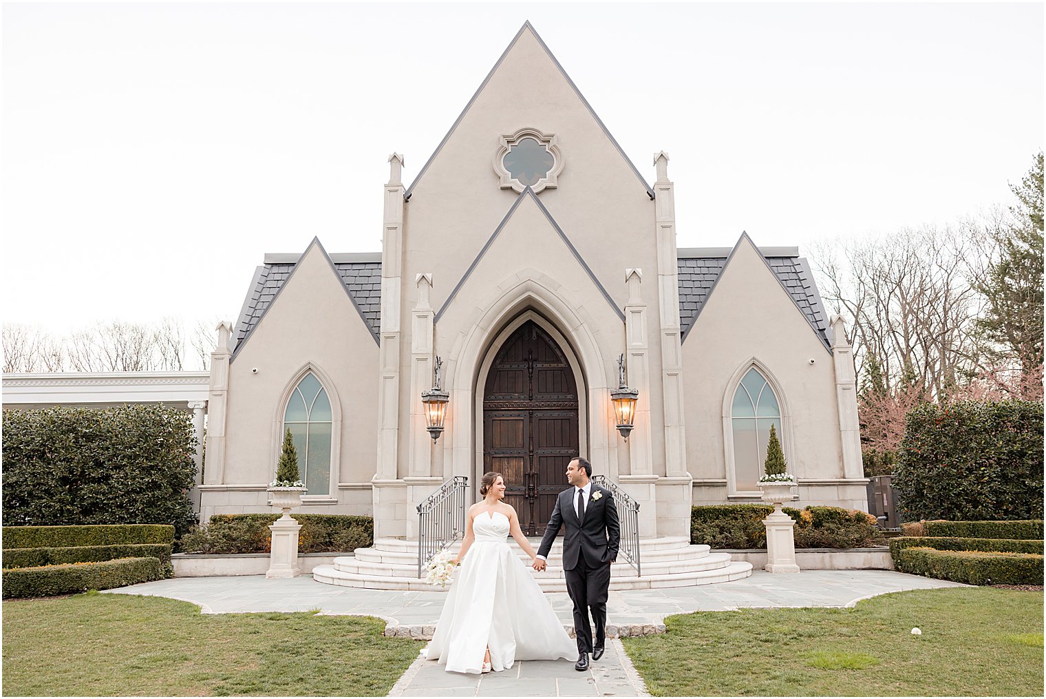 bride and groom hold hands walking outside Park Chateau Estate chapel