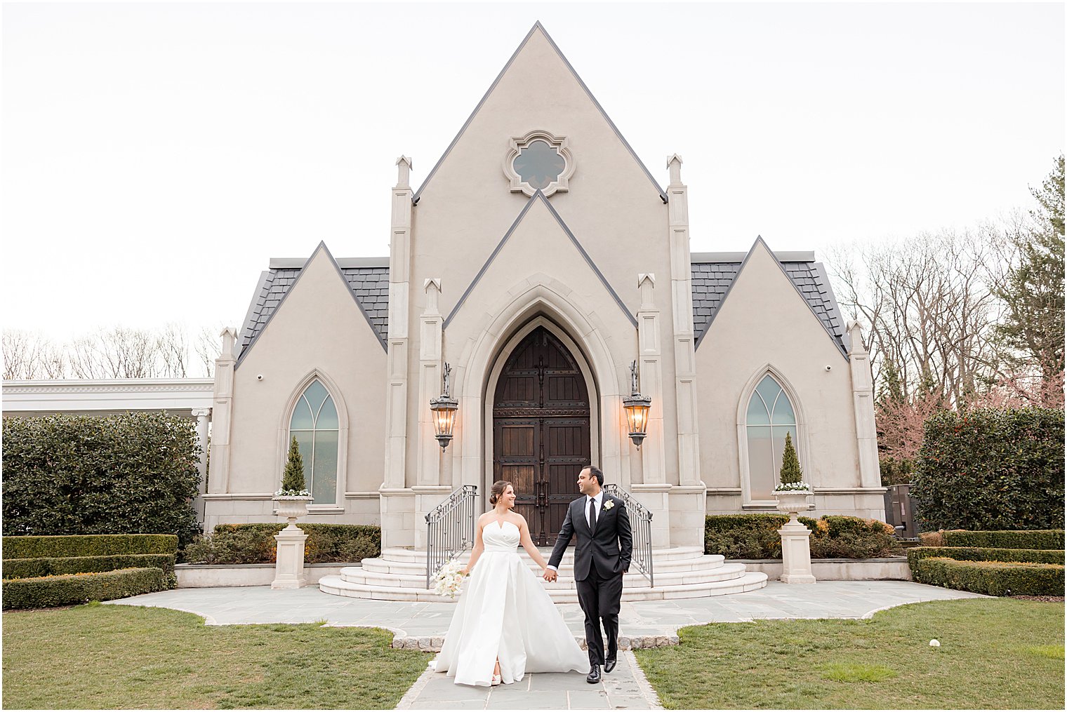 bride and groom hold hands walking outside Park Chateau Estate chapel 