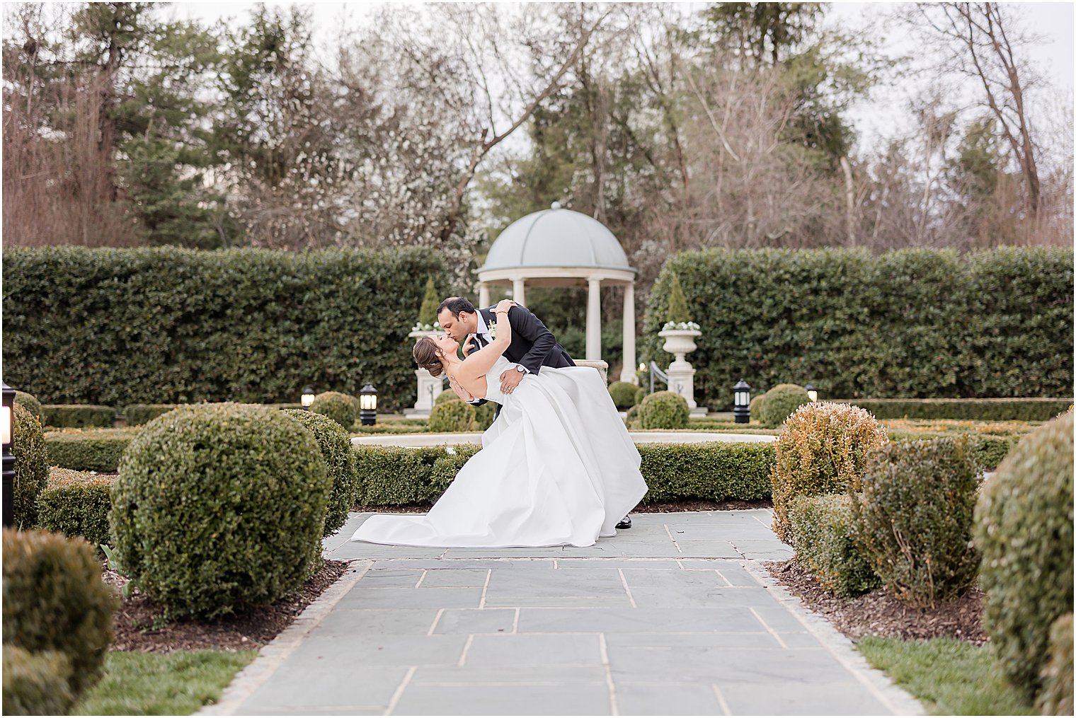 groom dips bride in the gardens at Park Chateau Estate