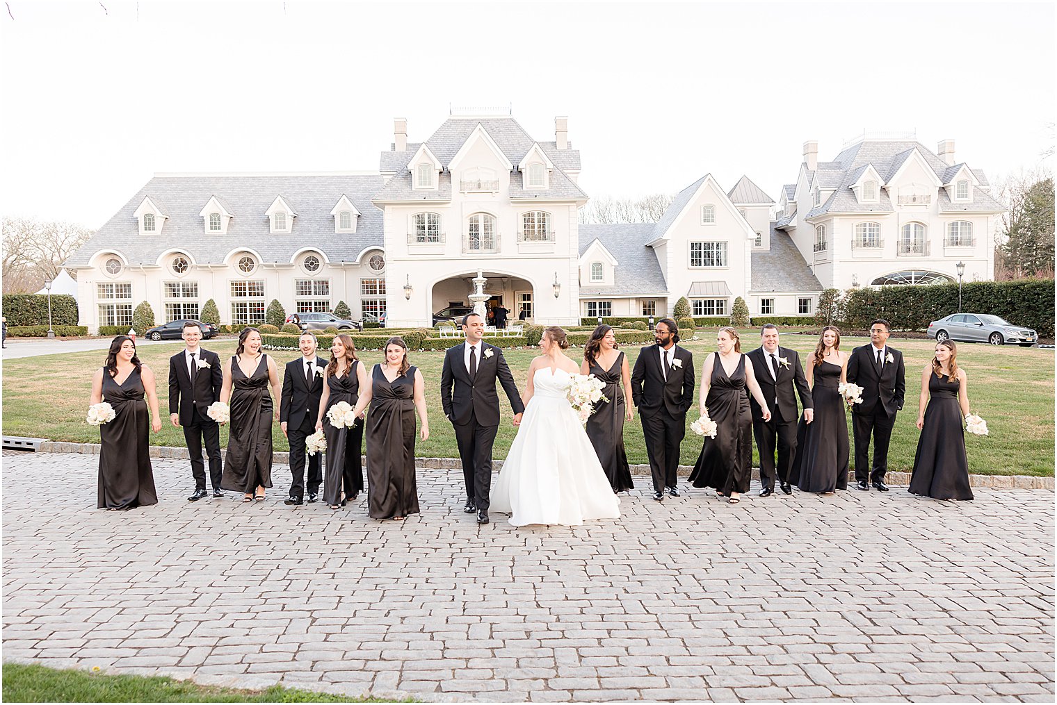 bride and groom walk with bridesmaids and groomsmen in black attire 