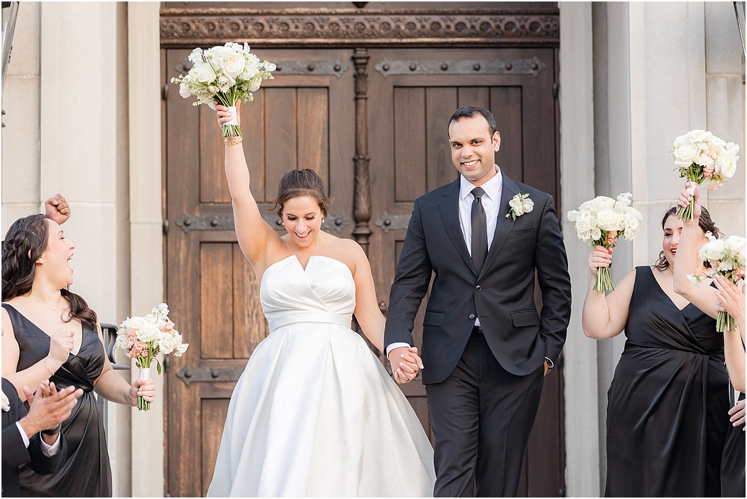 bride cheers raising bouquet of white flowers outside Park Chateau Estate chapel with groom