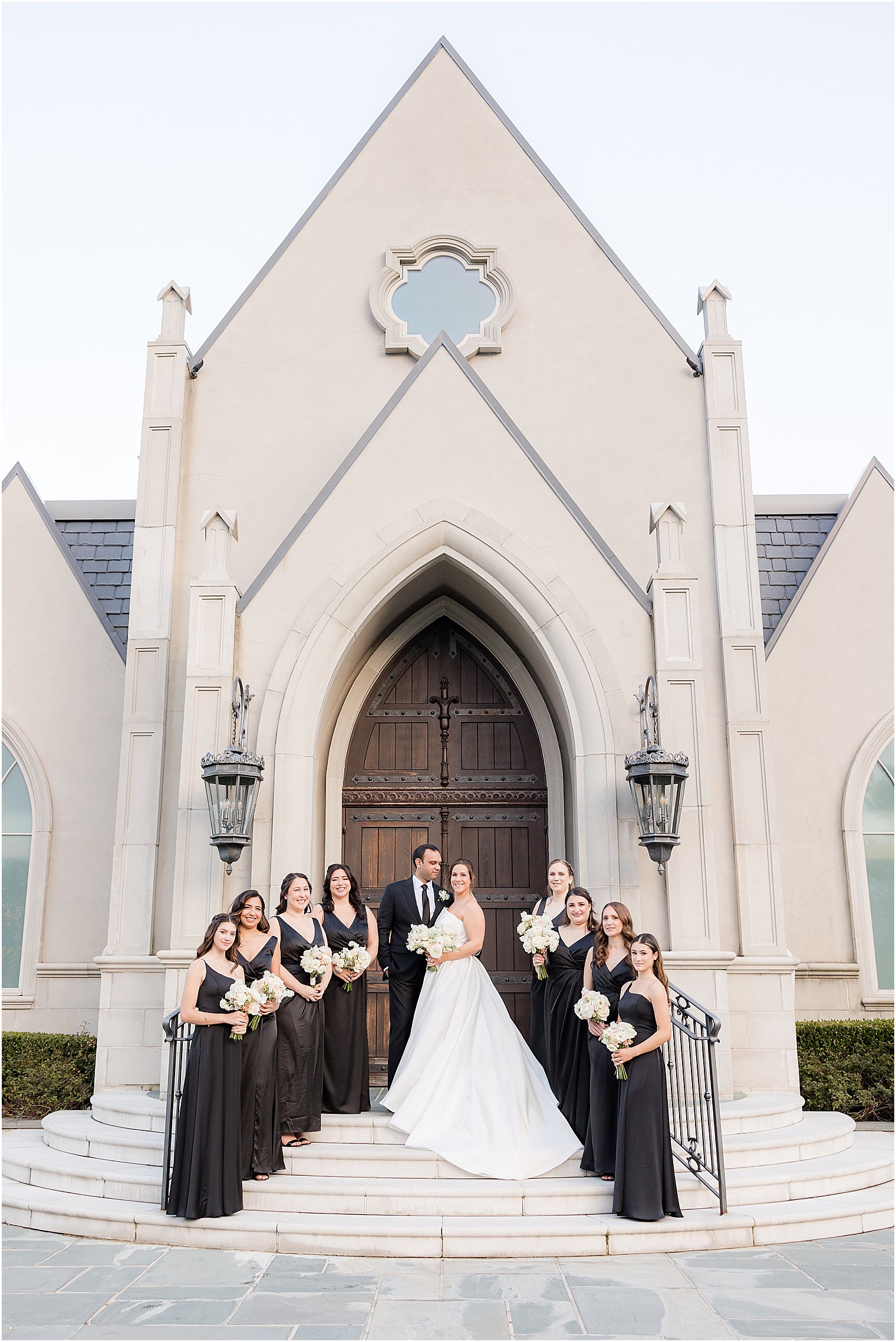 bride and groom stand on steps of Park Chateau Estate chapel with wedding party 