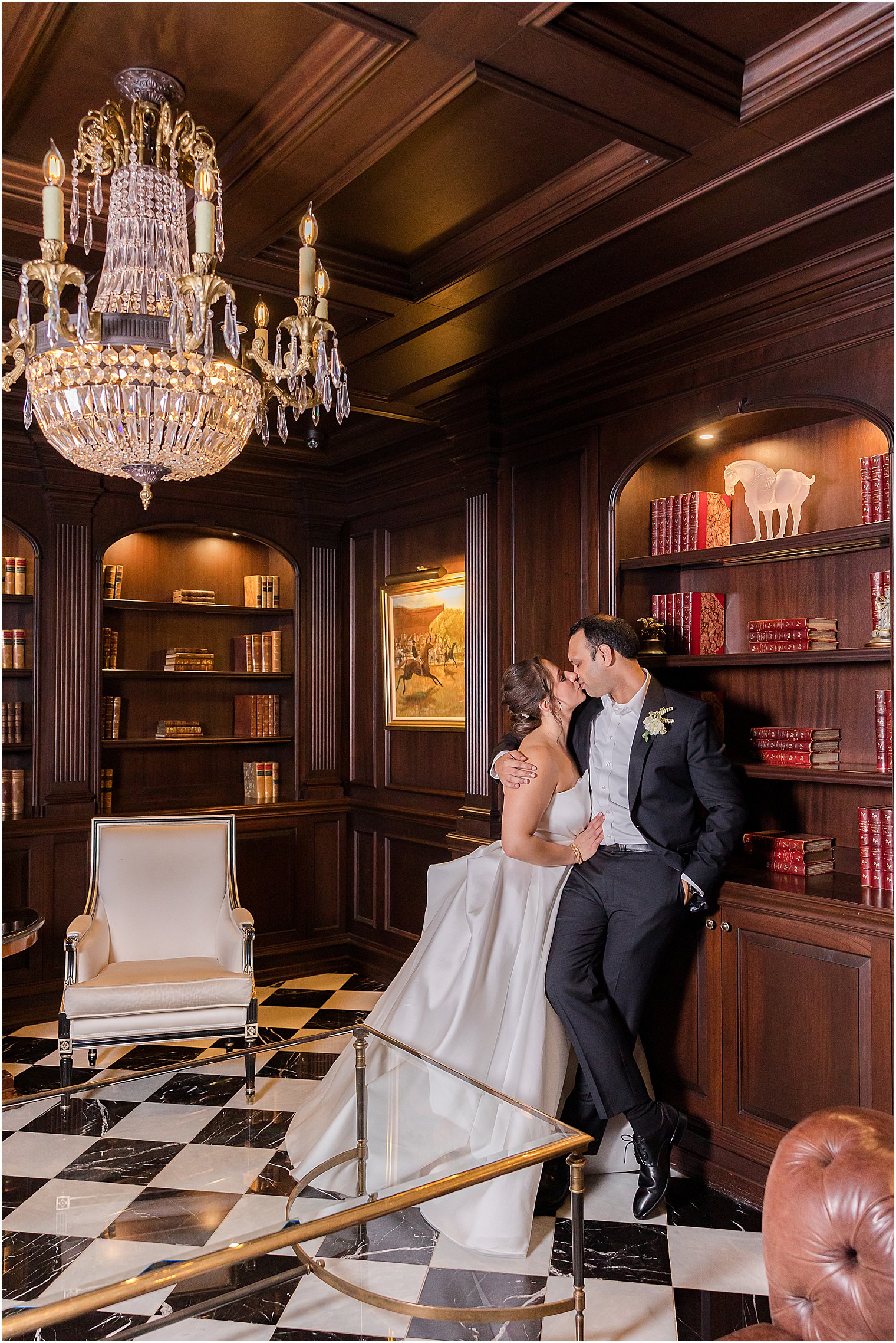 bride and groom lean for a kiss against bookcase at Park Chateau Estate