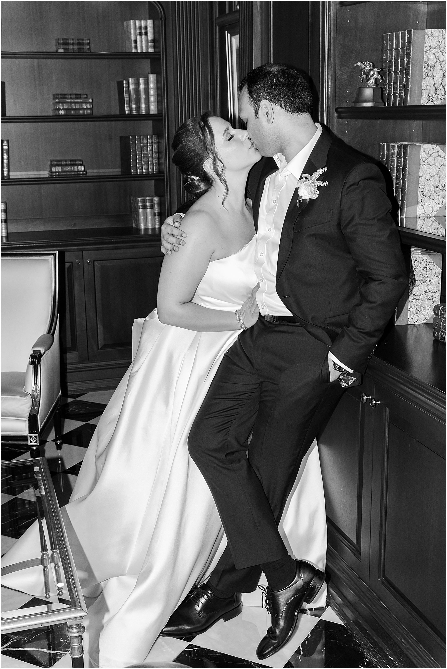 bride and groom lean for a kiss against bookcase at Park Chateau Estate