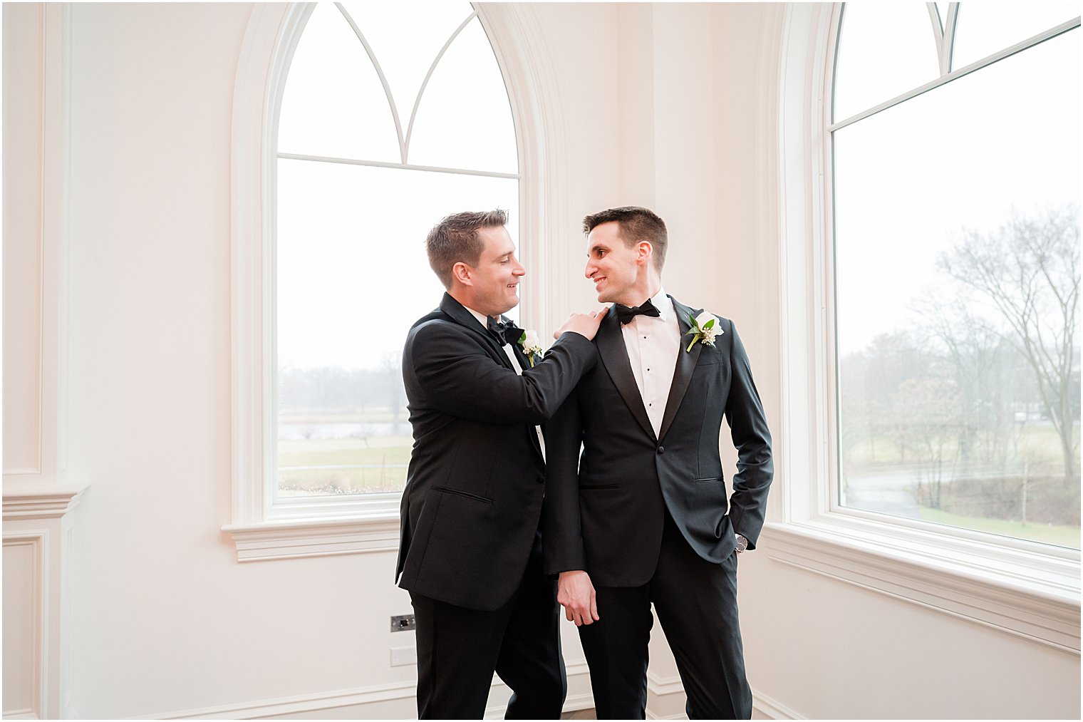 groomsman helps groom with jacket and tie