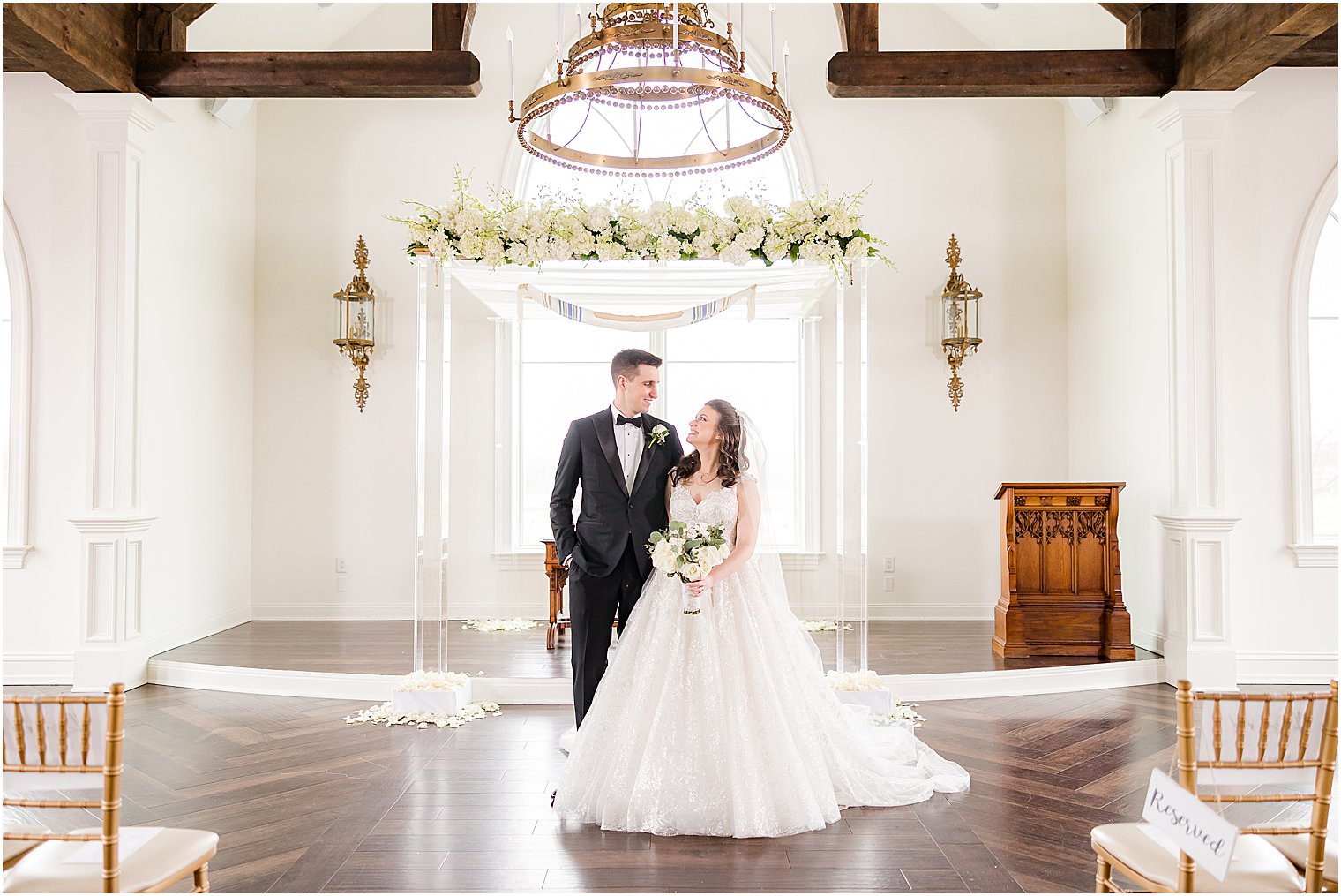 newlyweds smile together in front of chapel on rainy wedding day at Park Savoy Estate