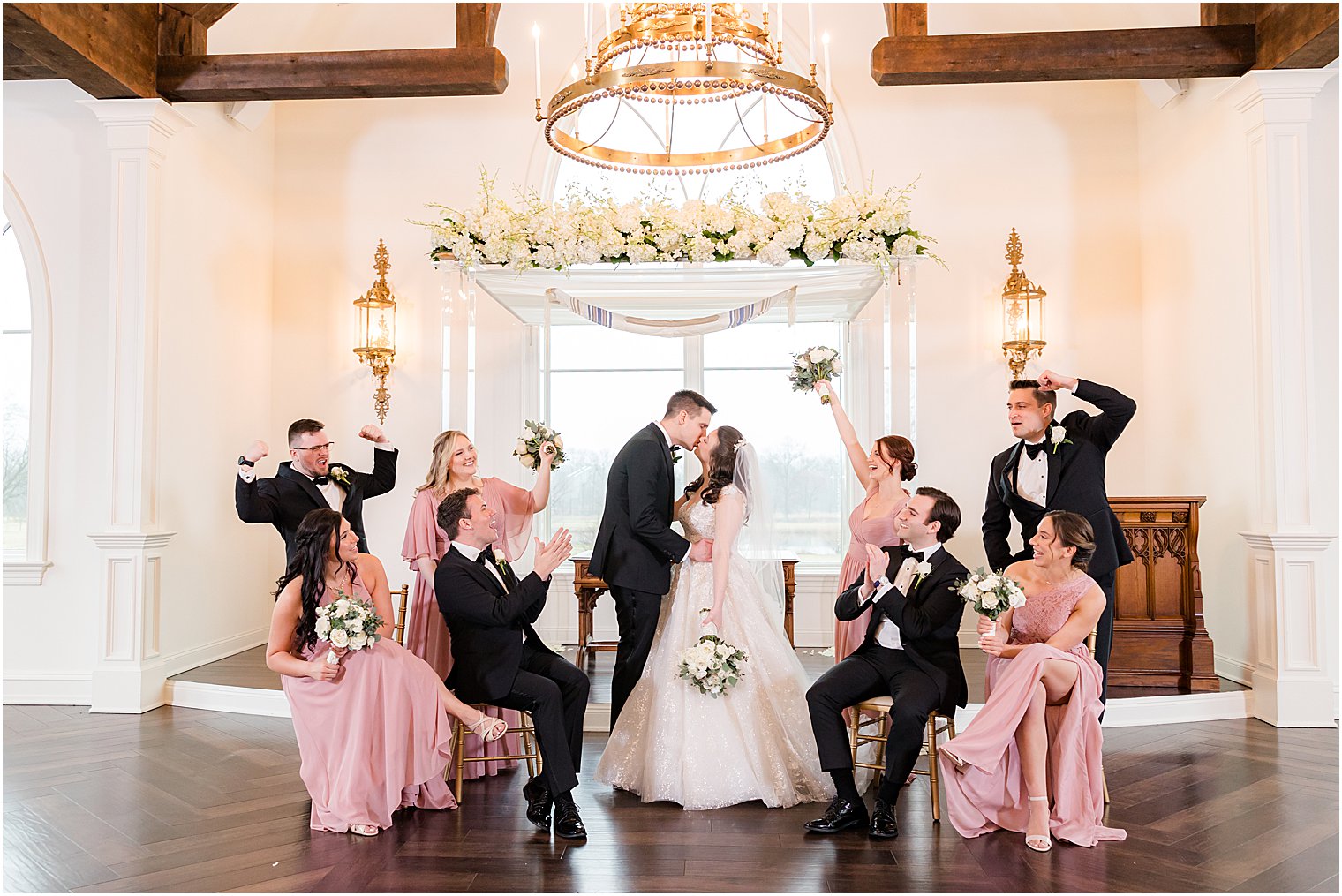 newlyweds kiss by chuppah at Park Savoy Estate with bridal party cheering around them 