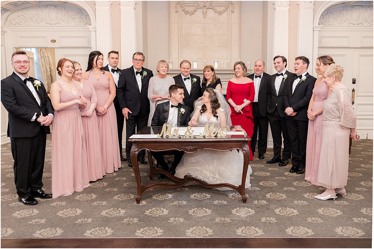 bride and groom sign Ketubah with family around them