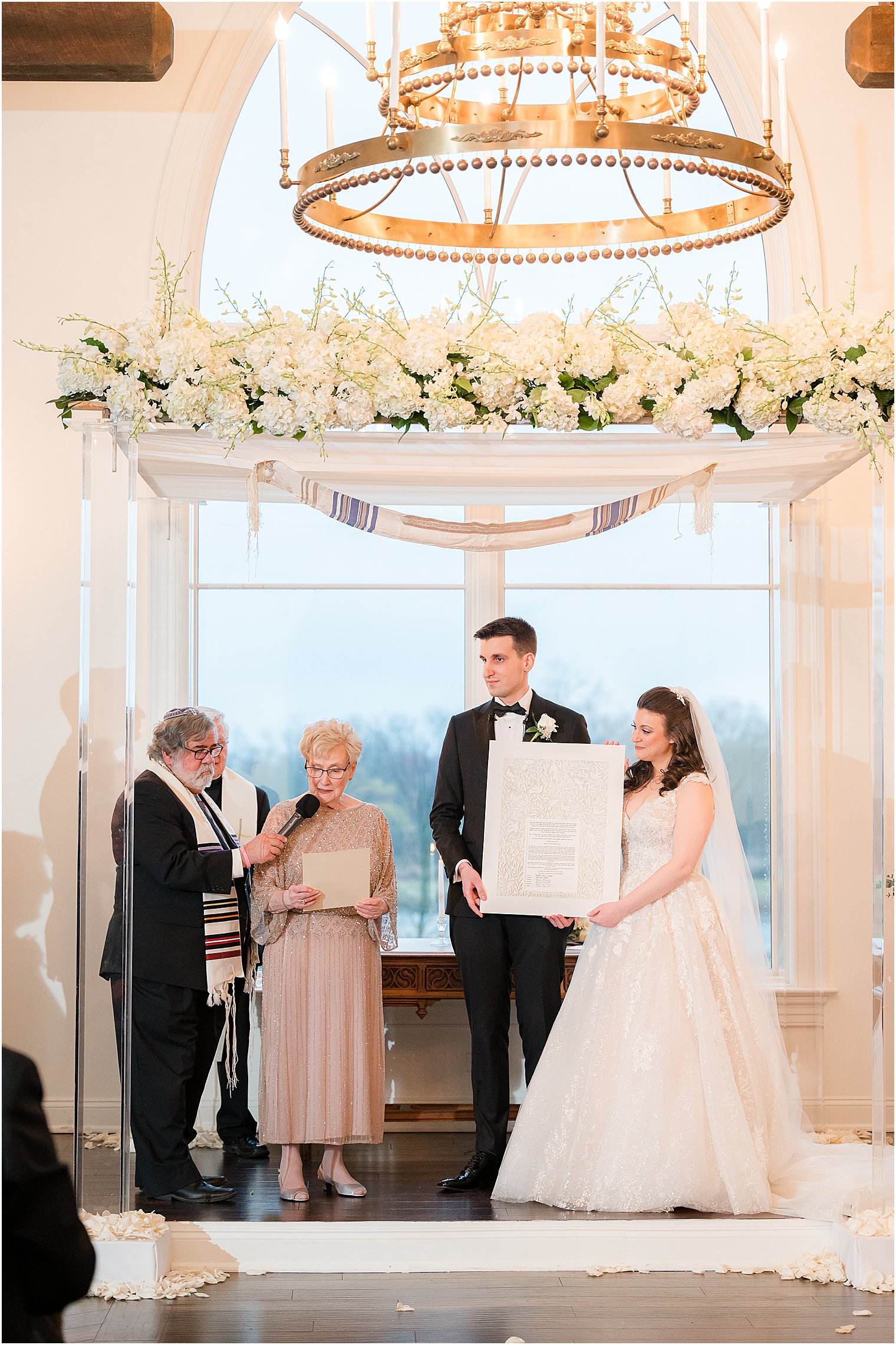 newlyweds hold Ketubah while woman speaks 