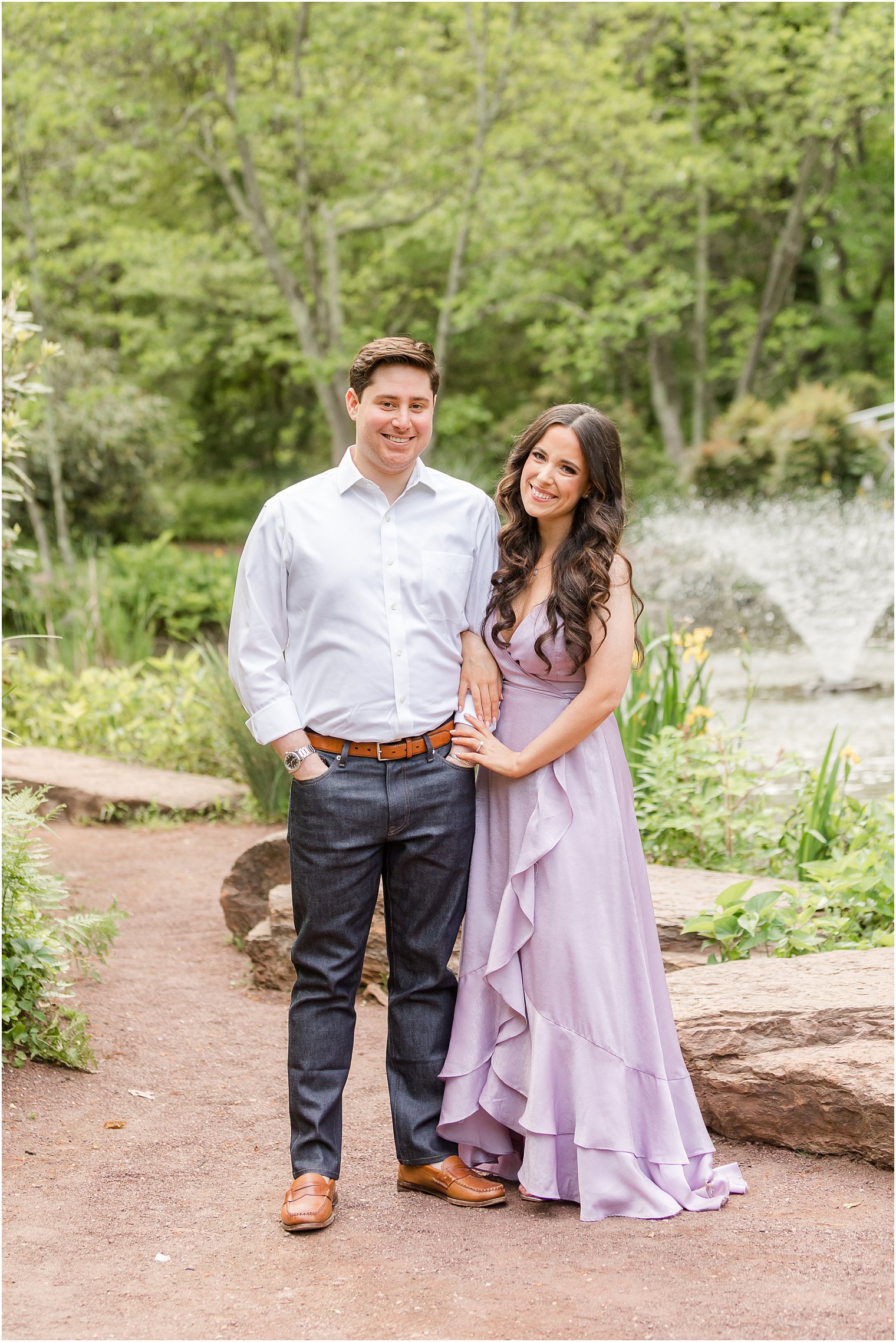 woman in purple dress holds hands with man in dress shirt and pants during Sayen Gardens engagement session